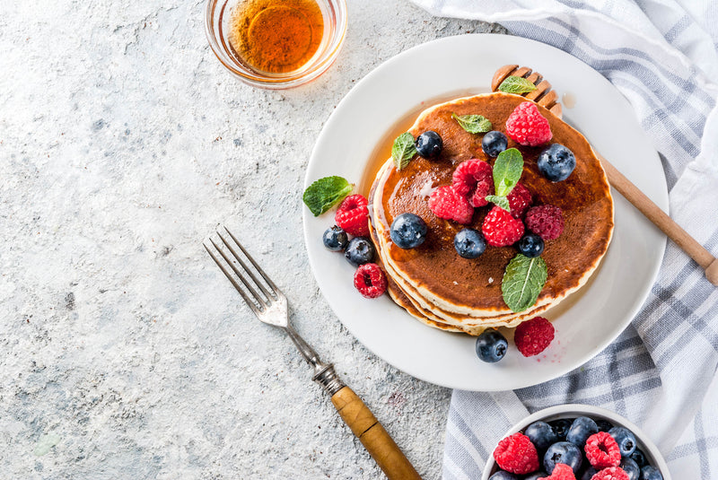 Protein Pancake Rezepte: Teller mit Pancakes, Obst und ein Schälchen mit Honig