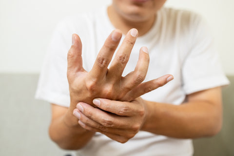 Mann hält sich die Hand fest