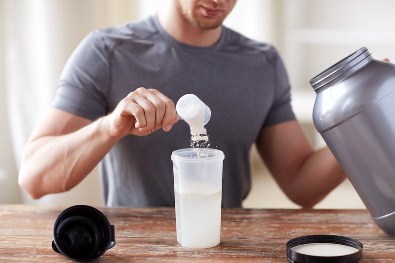 Pflanzliches oder tierisches Protein: Mann gibt Proteinpulver in einen Shaker