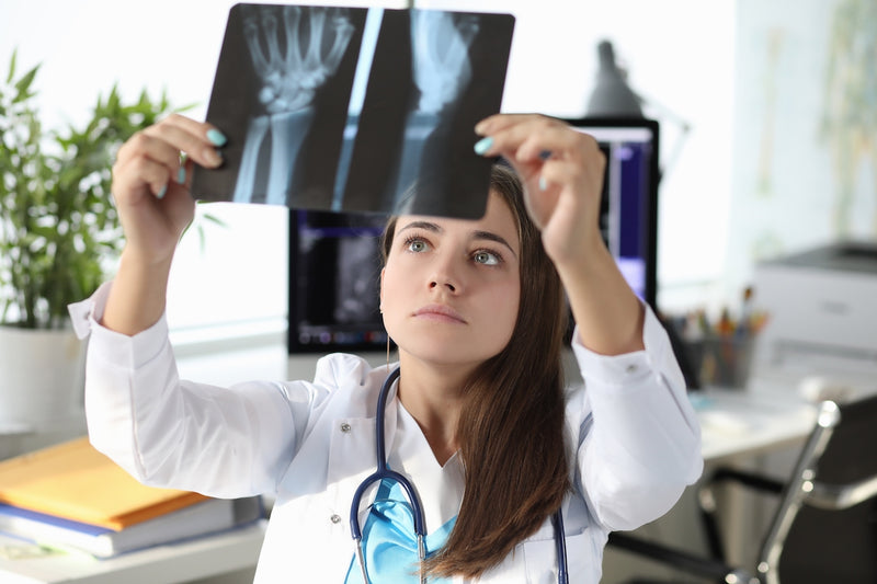 Ärztin schaut sich Röntgenbilder einer Hand an