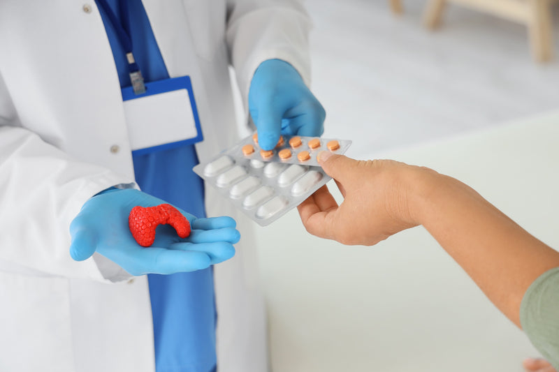Ein Arzt oder eine Ärztin reicht einer Patientin einen Medikamenten-Blister