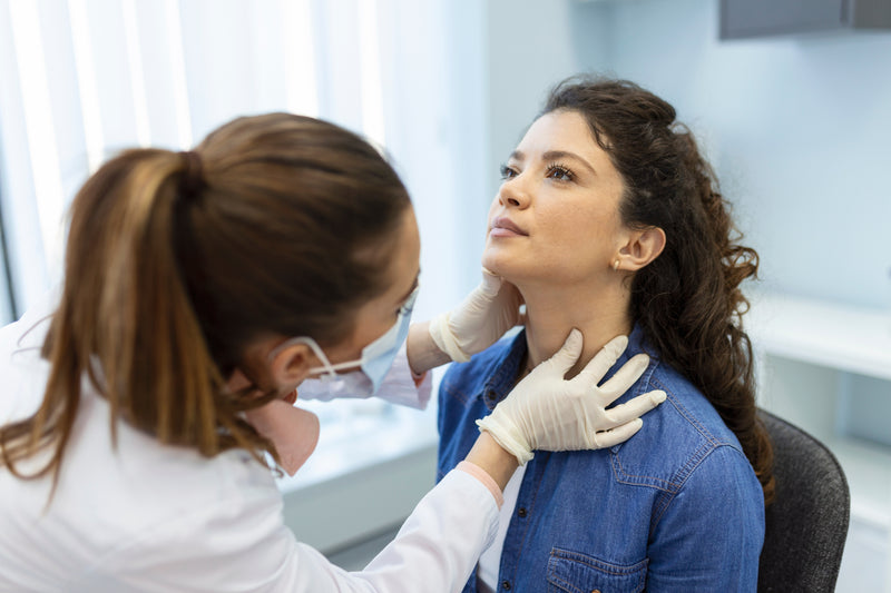 Ärztin tastet Schilddrüse einer Patientin ab