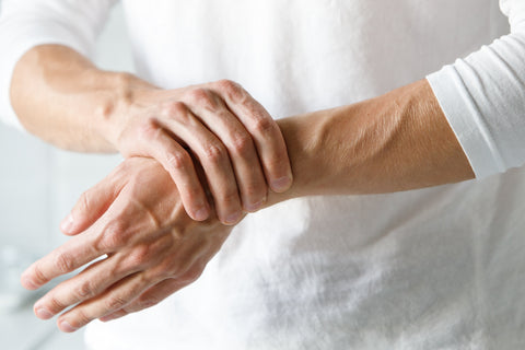 Eine Person greift sich an das schmerzende Handgelenk