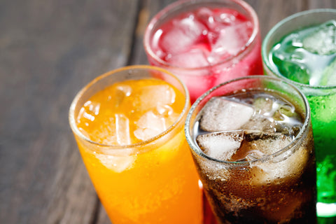 Mehrere Gläser mit bunten Softdrinks auf dem Bett