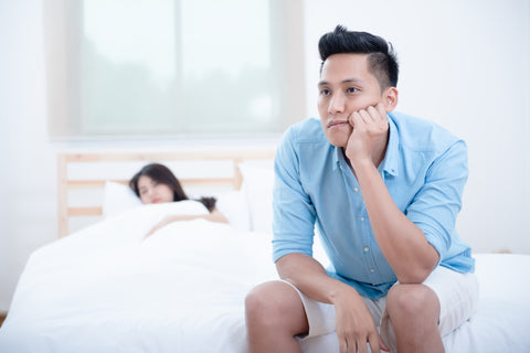 Mann sitzt frustriert auf dem Bett