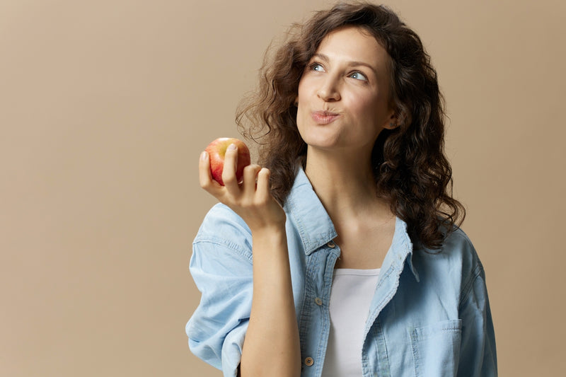 Verdauungsenzyme - Enzymproduktion unterstützen: Frau beißt in einen Apfel