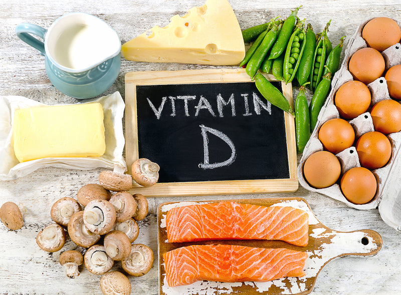 Vitamin D in Lebensmitteln: Ein Tisch mit Lebensmittel wie Eiern, Käse, Milch, Pilzen und Fisch ist zu sehen