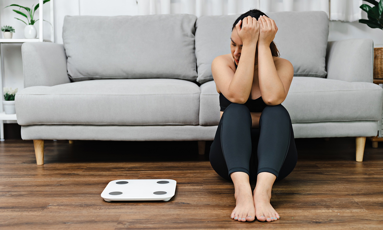 Frau sitzt frustriert neben einer Waage