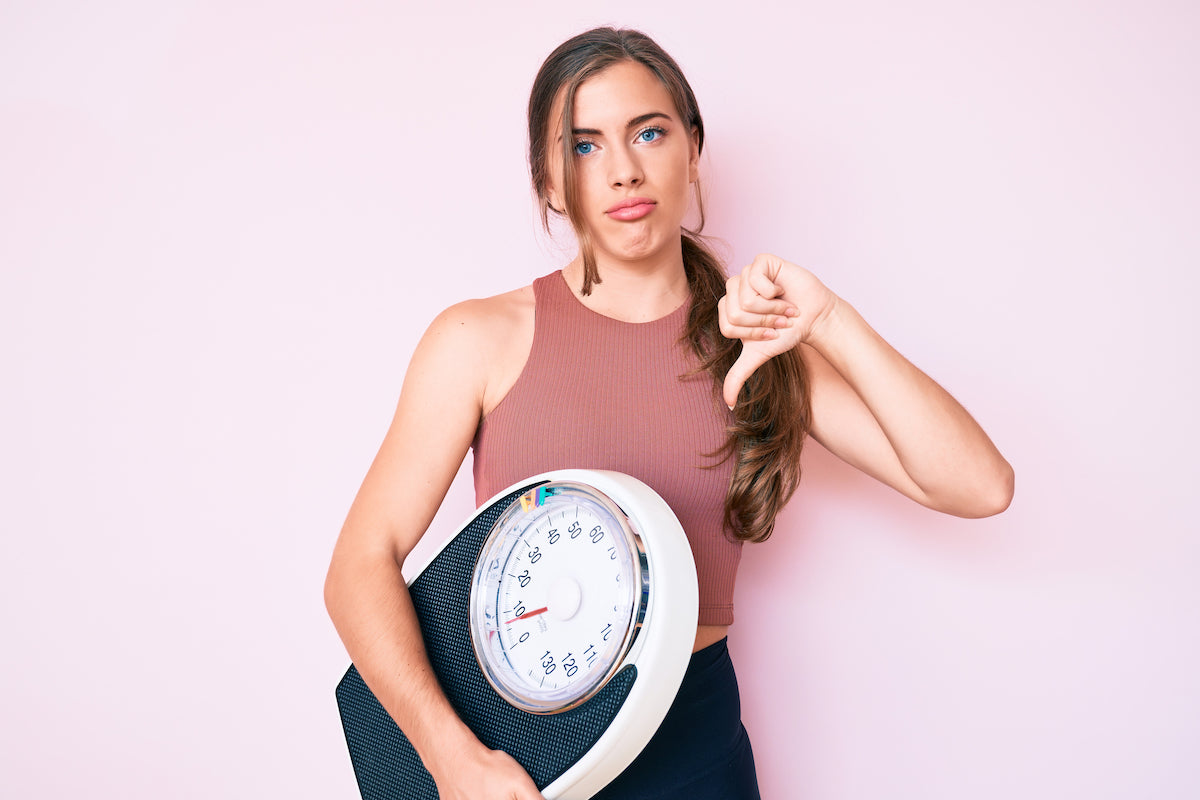 Frau mit Waage zeigt Daumen nach unten