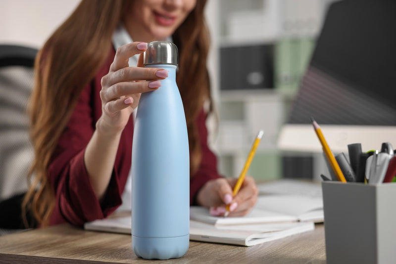 Eine Frau greift nach einer Flasche Wasser auf dem Tisch