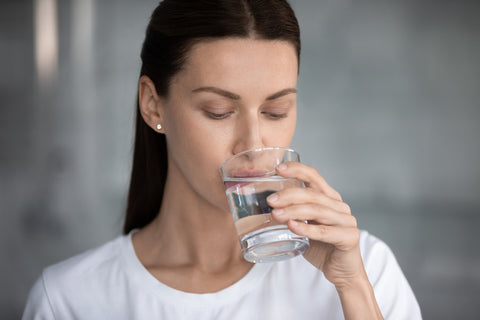Eine Frau trinkt aus einem Glas Wasser