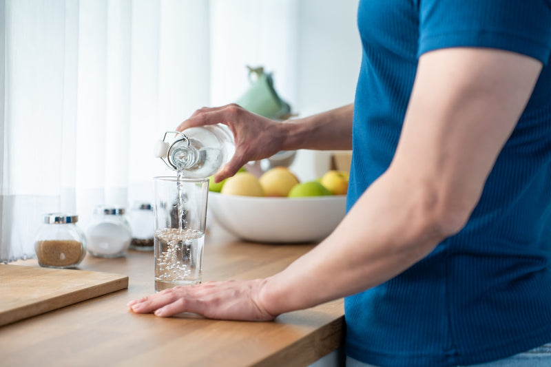 Ein Mann schenkt sich Wasser in ein Glas ein