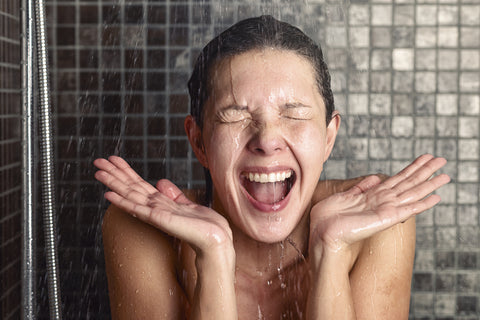 Frau steht mit weit geöffnetem Mund unter der Dusche