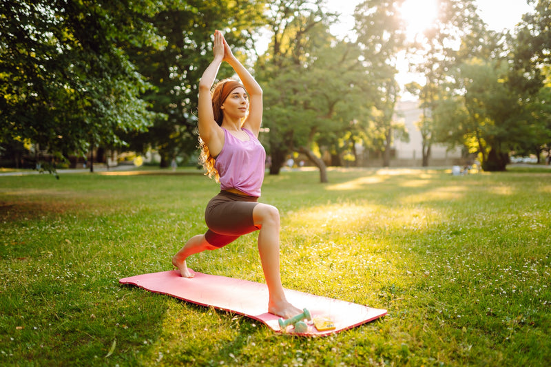 Eine Frau macht Yoga auf einer Matte im Park