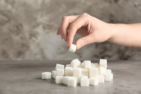 Hand legt Zuckerwürfel auf einen Haufen