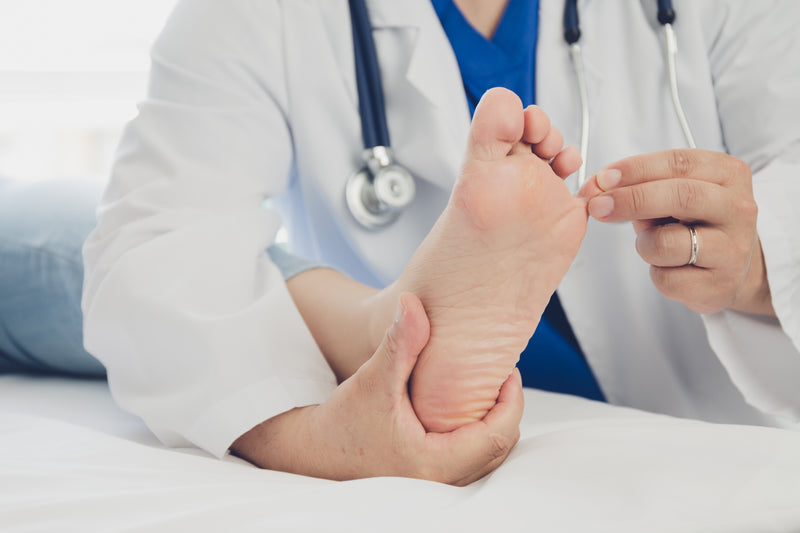 Arzt behandelt Fuß eines Patienten