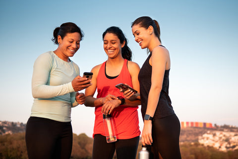Fitness-Tracker Gesundheit: Drei Frauen vergleichen die Ergebnisse auf ihren Handys und Fitnessuhren miteinander