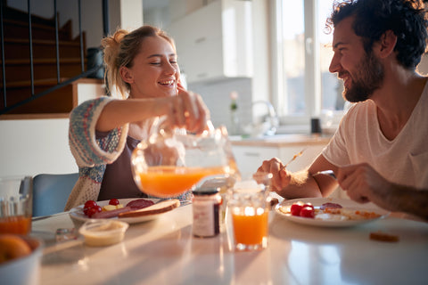 Frau schenkt Mann zum Frühstück Saft ein