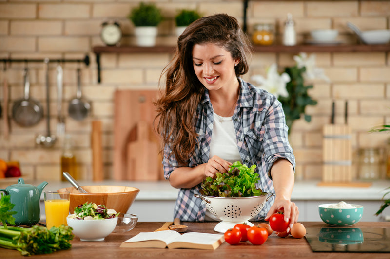 Frau steht in der Küche mit gesunden Nahrungsmitteln