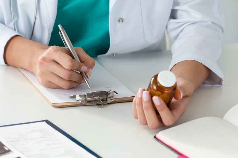 Chrom einnehmen: Arzt hält Dose mit Wirkstoff in der Hand und notiert etwas auf einem Klemmbrett