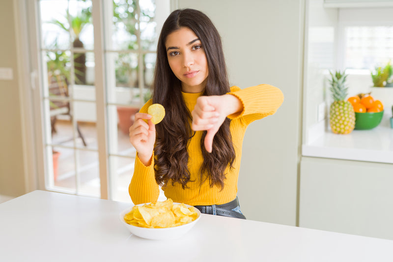 Frau zeigt Chips und Daumen nach unten