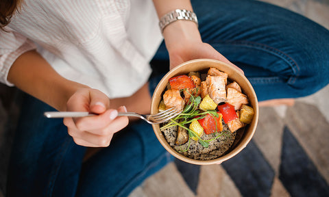 Eine Frau isst eine gesunde Bowl mit Paprika und Lachs