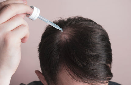 Schwarzkümmelöl Wirkung: Mann tropft sich Schwarzkümmelöl auf die Kopfhaut