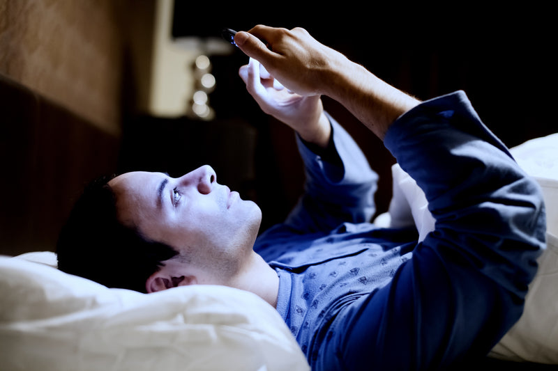 Person nutzt Smartphone im Bett vor dem Schlafen