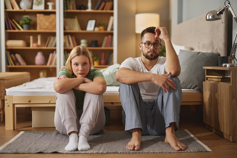 Ein paar sitzt schweigend während des Streits am Bett angelehnt