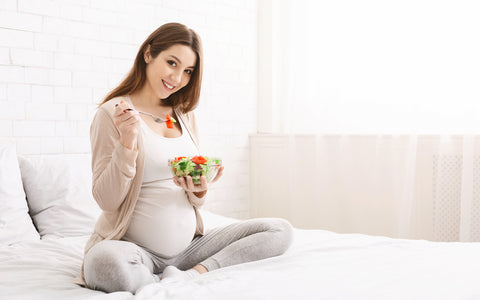 Schwangere Frau isst einen Salat