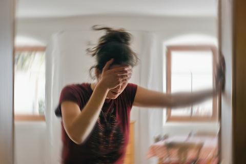 Eine Frau hält sich aufgrund einer Schwindelattacke am Türrahmen fest